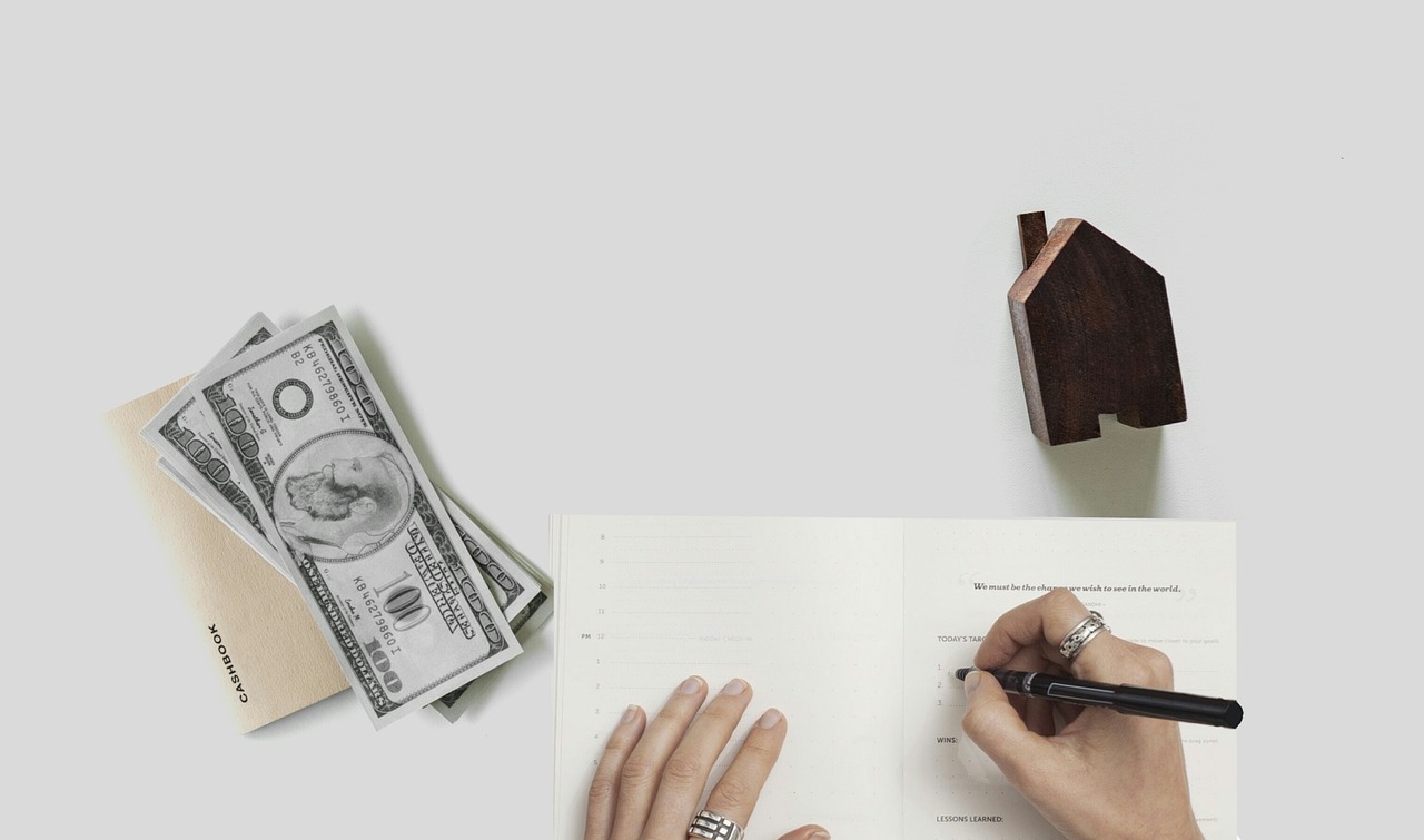 A person writing financial notes with cash and a wallet nearby, symbolizing budgeting and emergency fund planning