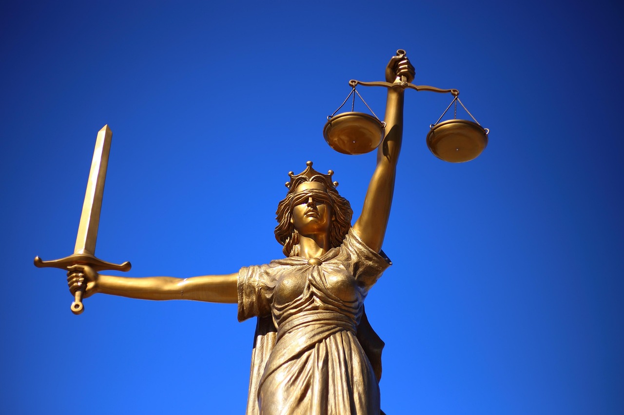 A golden statue of Lady Justice holding a scale and a sword, symbolizing fairness, legal integrity, and the rule of law